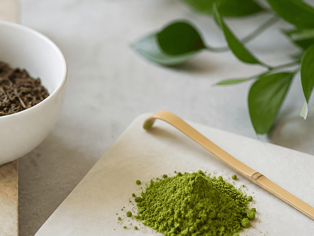 Matcha powder with tea leaves and a bamboo scoop